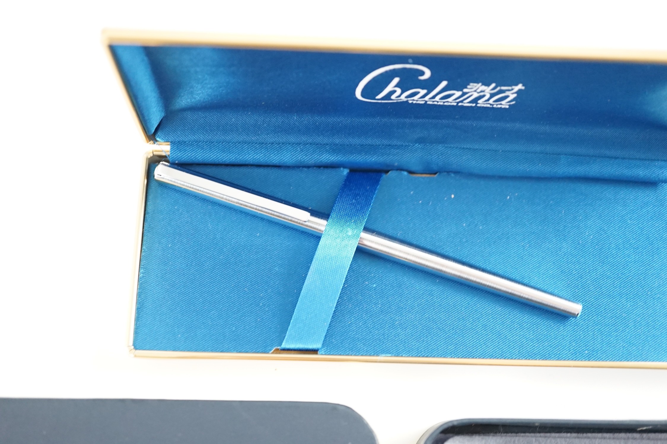 An S de Cartier navy blue leather cigarette case with blue cabochon set clasp, 11 cm., boxed and a Chalana note pen, cased.